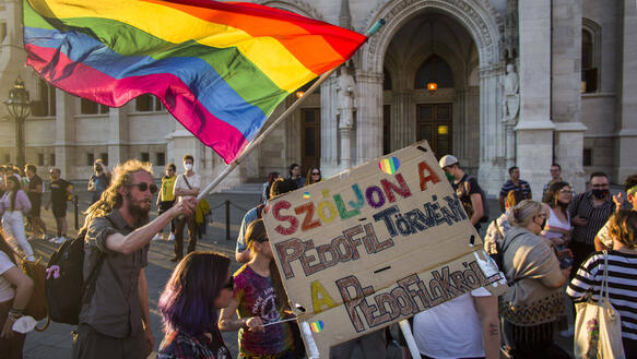 Das Bild zeigt Demonstrant_innen mit Regenbogenfahnen und Plakaten.
