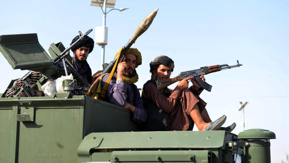 Das Bild zeigt mehrere Männer mit schweren Waffen auf einem Militärfahrzeug