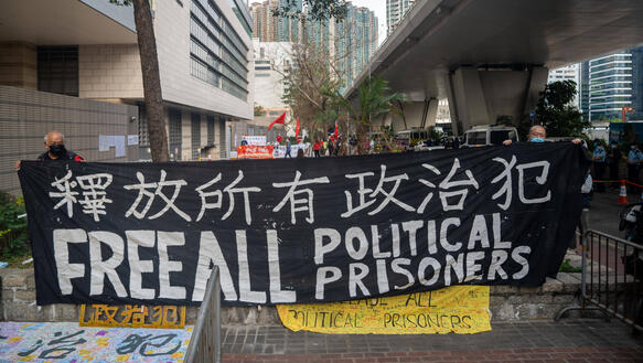 Das Bild zeigt ein großes Protest-Banner "Free all political prisoners"