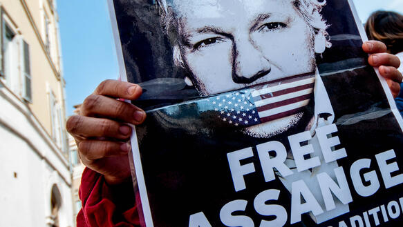 Das Bild zeigt ein Plakat mit einem Foto von Julian Assange und dem Titel "Free Assange"