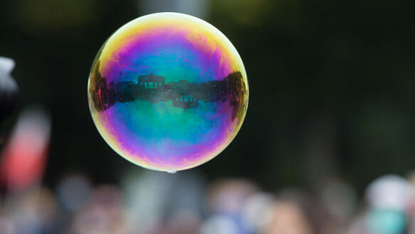 In einer Seifenblase, die in der Luft hängt, spiegelt sich das Brandenburger Tor.