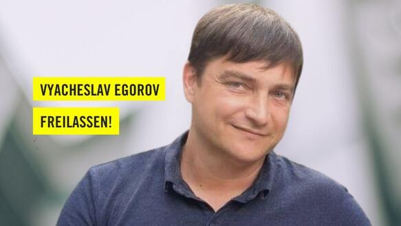 Portraitfoto eines Mannes vor einem unklaren Hintergrund. Neben seinem Kopf steht auf gelbem Grund "Der russische Umweltaktivist Vyacheslav Egorov freilassen!".