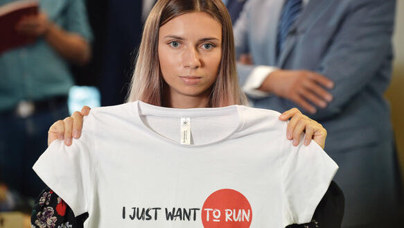 Eine junge blonde Frau hält ein T-Shirt zwischen ihren Händen gespannt auf dem steht "I just want to run".