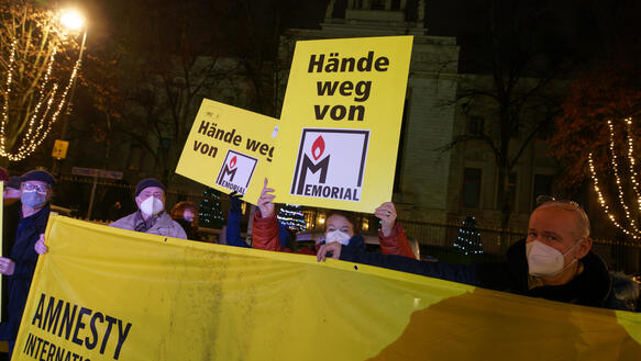 Das Bild zeigt Menschen mit "Hände weg von Memorial"-Plakaten hinter einem großen Amnesty-Banner vor der russischen Botschaft.