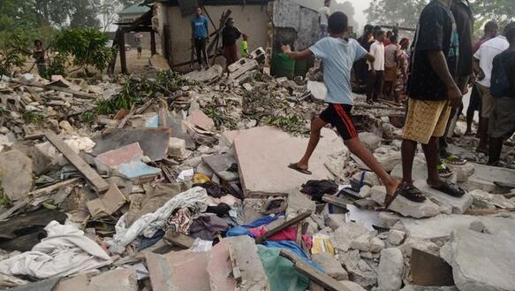 Anwohner_innen der nigerianischen Stadt Port Harcourt stehen in den Trümmern ihrer Häuser