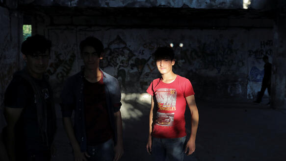 Zwei junge Afghanen in T-Shirts stehen in einer alten verlassenen Fabrik und posieren für ein Foto.