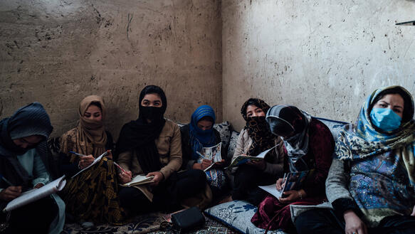 Das Bild zeigt mehrere Frauen, die mit Büchern am Boden sitzen