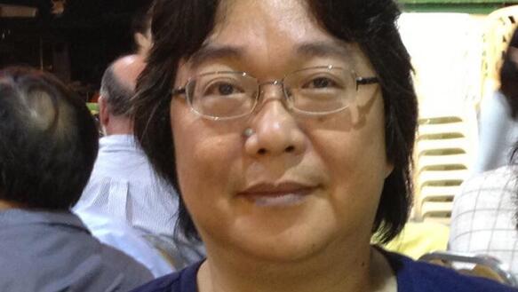 Das Bild zeigt eine Portraitaufnahme von Gui Minhai, der in die Kamera schaut und eine Brille trägt.