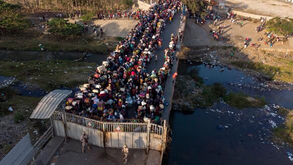 Auf einer Brücke steht eine Menschenmenge vor einer Absperrung.