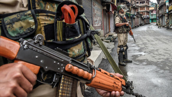 Eine Militärpatrouille mit Maschinengewehren steht auf einer Straße in Kaschmir.