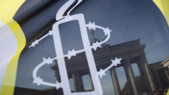 Die Amnesty-Kerze auf einer Flagge, im Hintergrund das Brandenburger Tor