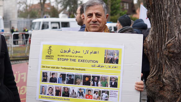 Das Bild zeigt einen Mann mit einem Protestplakat