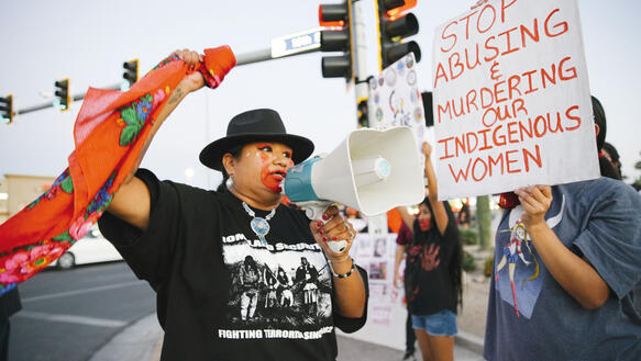Indigene Frauen demonstrieren vor einer Ampel auf einer Straße in den USA.