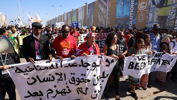 Protestzug mit Transparent, auf dem in Arabisch steht: "Es gibt keine Klimagerechtigkeit ohne Menschenrechte."