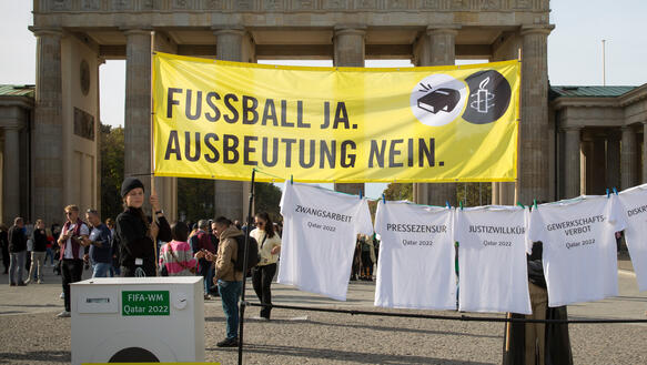 Das Bild zeigt ein gelbes Banner und eine Wäscheleine mit T-Shirts
