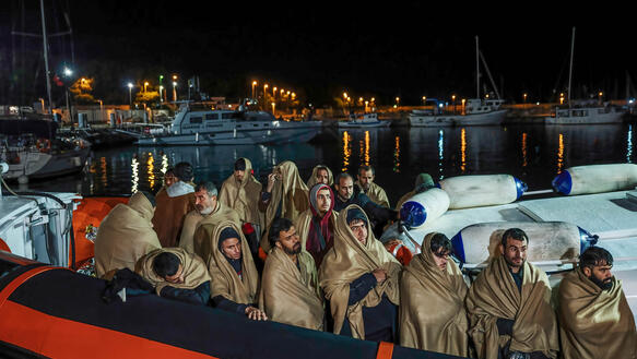 In Decken gehüllte Menschen auf einem Boot