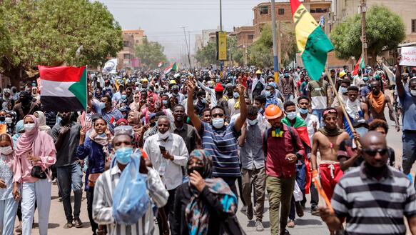 Eine protestierende Menschenmenge mit sudanesischen Flaggen