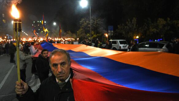 Menschen mit Fackeln und einer langen armenischen Fahne