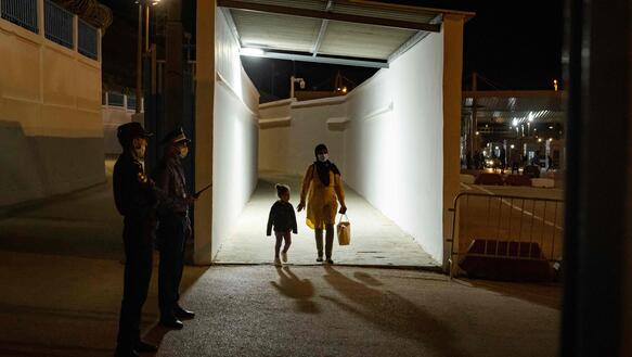 Eine Frau mit Kind kommt aus einem Tunnel, daneben Sicherheitskräfte.