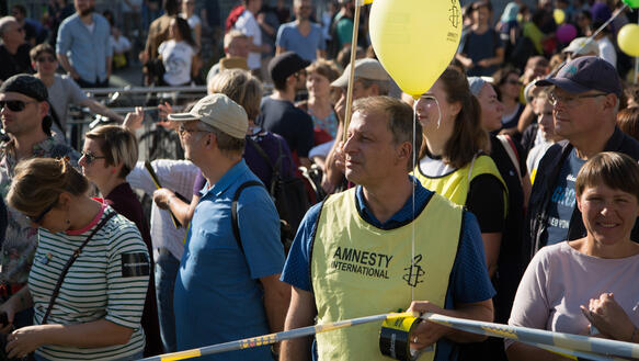 Das Bild zeigt ein Mann, der eine gelbe Amnesty-Weste trägt. Er steht in einer Menschenmenge. Wir werden ihn vermissen.