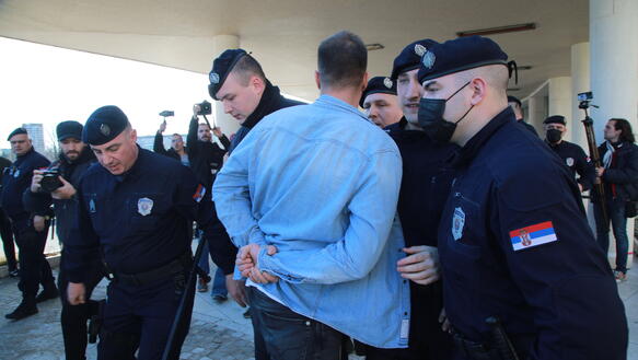 Sicherheitskräfte verhaften einen Mann in blauem Hemd