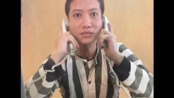 Ein Mann in einem schwarz-weiß-gestreiften Anzug hält sich an beide Ohren je ein Kabeltelefon. Es ist Nguyễn Văn Chưởng. 