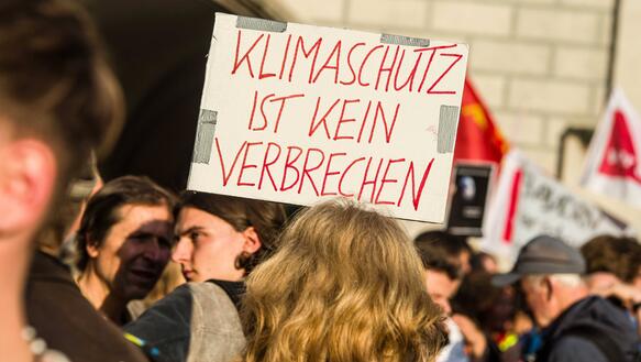 Das Bild zeigt ein Protestschild auf dem steht: "Klimaschutz ist kein Verbrechen"