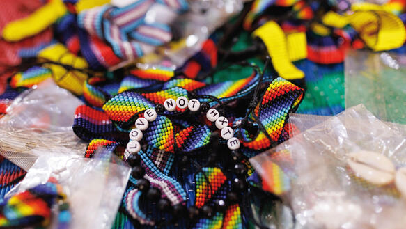Armbänder, die verziert sind mit Buchstaben: "Love not hxte", liegen auf einem Tisch.