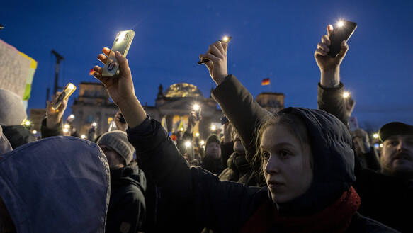 Das Bild zeigt Menschen, die protestieren. Sie halten ihre Handys in die Höhe