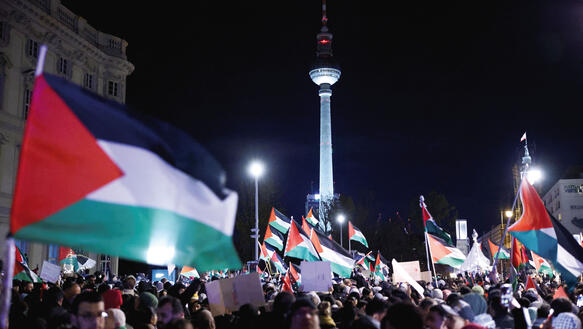 Menschen in Berlin auf der Straße mit palästinensischen Flaggen: eine Demonstration, im Hintergrund der Fernsehturm am Alexanderplatz