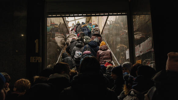 Menschen stehen dicht an dicht auf einer Treppe, die aus einem Bahnhof nach oben führt.