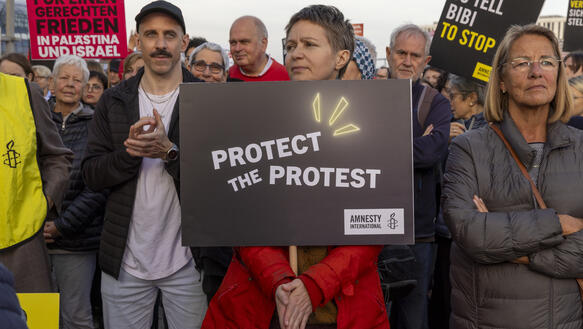 Das Bild zeigt eine Person mit einem Protestplakat