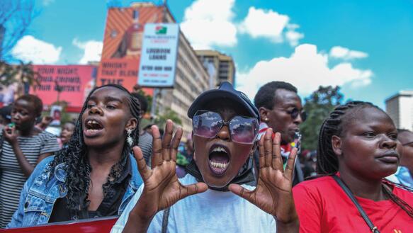 Demonstrantinnen auf einer Demo in Nairobi schreien, eine Frau trägt eine Baseballmütze.