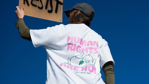 junge Frau im Amnesty T-Shirt "Human Rights are hot" und einem Resist Protest Plakat