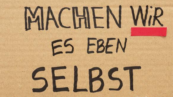 Ein Karton mit Filzer beschrieben: "Dann machen wir es eben selbst", darunter gedruckt Engagement der Zivilgesellschaft, das ganze ist das Cover des Amnesty Journals, Ausgabe 1/2026