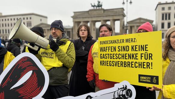 Mehrere Menschen protestieren mit Plakaten und Megaphon
