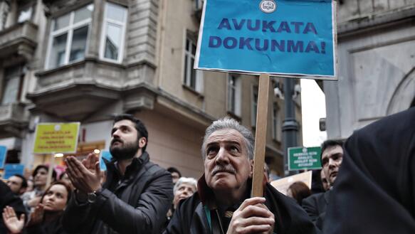 Ein Mann steht inmitten von Menschen mit einem Protestplakat