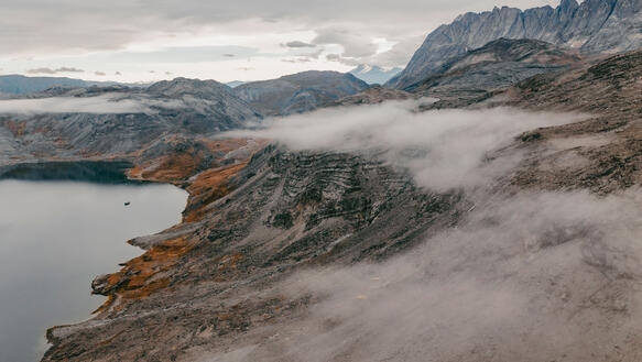 Landschaft in Grönland, zerklüftete Hügelketten, die sich vom Wasser aus emporheben und bis zum Horizont erstrecken.
