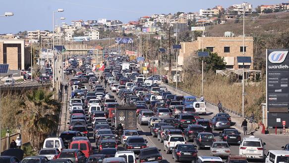 Das Foto zeigt eine mit mindestens 100 Autos vollgestopfte Straße am Rande einer Stadt.