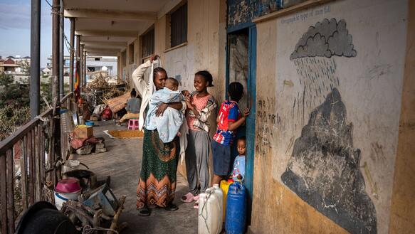 Das Foto zeigt zwei Fauen und drei Kinder auf dem Gang und in der Tür zu einem Raum stehen.