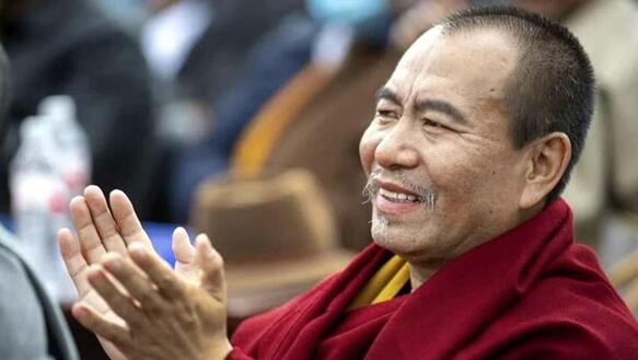 Seitenaufnahme von Choktrul Dorje Ten Rinpoche. Er lächelt und klatscht in die Hände.