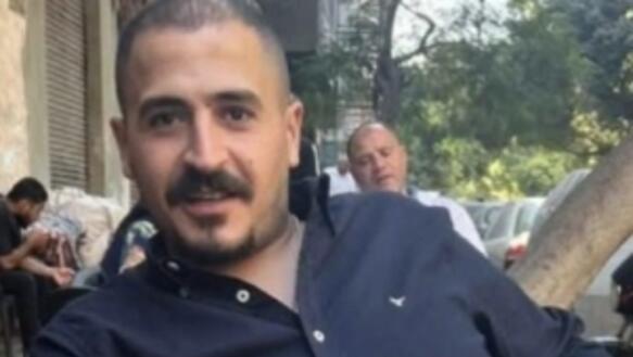 Porträtfoto von Said Abdelrazek, mutmaßlich aufgenommen im Außenbereich eines Cafés. Er trägt ein Hemd, dessen obere Knöpfe offen sind. Er lächelt in die Kamera.