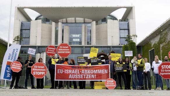   Menschen bei Protestaktion vor dem Kanzleramt in Berlin mit Transparenten und Schildern