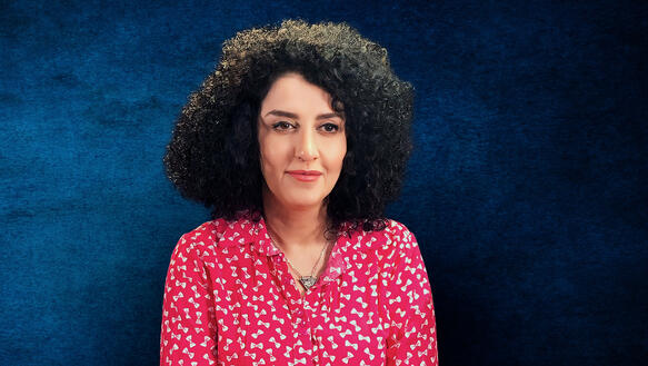 Porträtaufnahme von Narges Mohammadi. Sie trägt ein Hemd und ihre Haare offen.