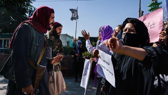 Frauen bei einem Demonstrationszug stehen Männern gegenüber.