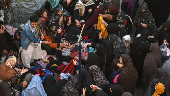 Afghanische Menschen auf einem Markt suchen Klaiedung aus.