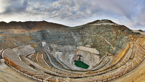 Ein kreisrundes Loch in der Landschaft, ein Krater, der durch Bergbau entstanden ist, Terrassen führen in die Tiefe, am Grund ist ein See entstanden, dort sammelt sich Wasser.