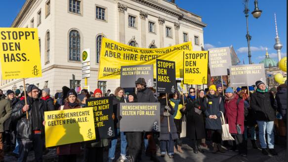 Das Foto zeigt eine große Personengruppe mit Amnesty-Schildern bei einer Kundgebung, auf denen unter anderem steht: "Stoppt den Hass".