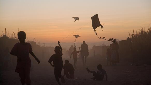 Kinder spielen mit Drachen im Sonnenuntergang