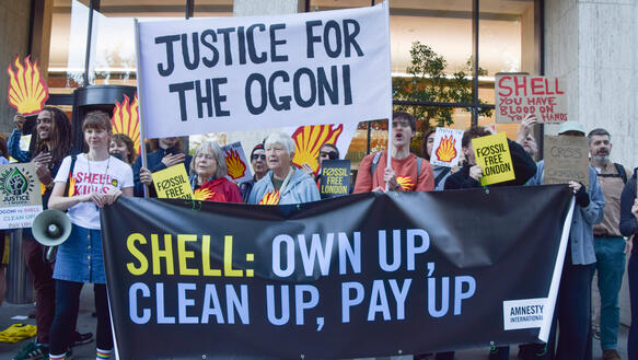 Demonstration mit Protestschildern und Shell-Zeichen